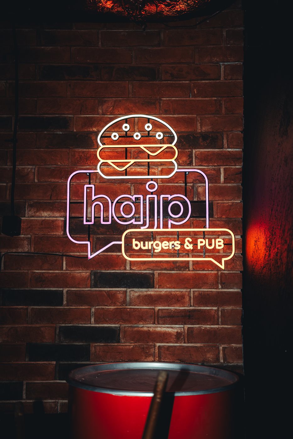 Neon logo Hajp Burgers and Pub na ceglanej ścianie lokalu, świeci bez pleksi