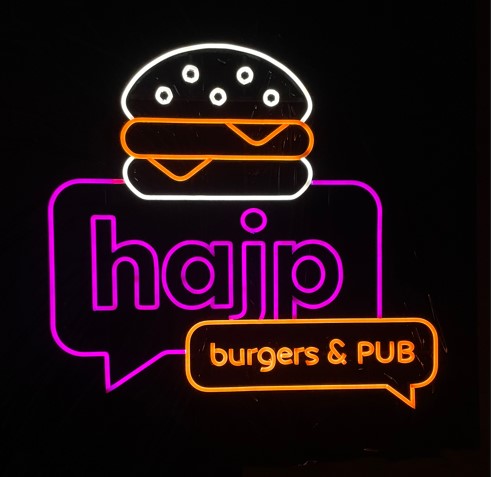 Neon logo Hajp bez pleksi na ceglanej ścianie lokalu, widoczny sam świecący kształt